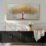 Large gold tree of life wall art displayed above a modern black cabinet with decor and flowers.