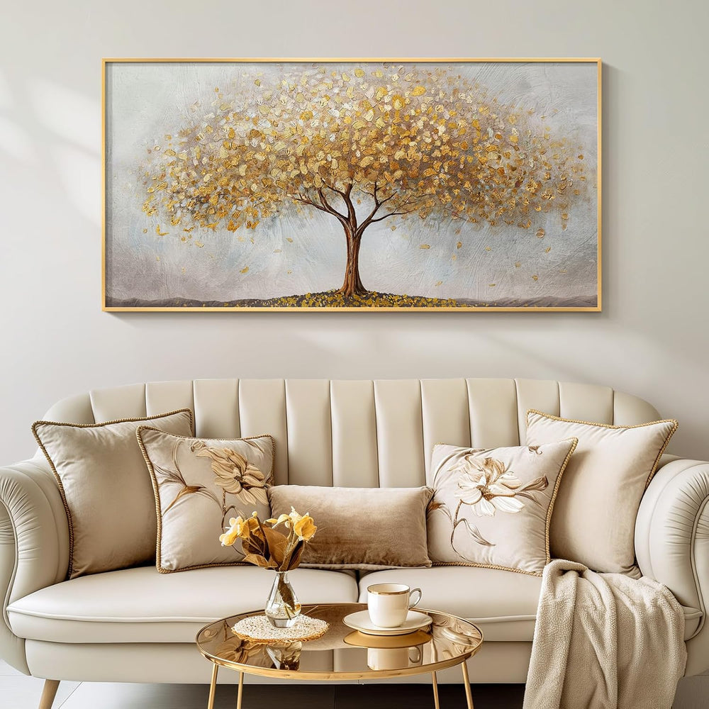 Large gold tree of life wall art displayed above a stylish couch with floral pillows and a coffee table.