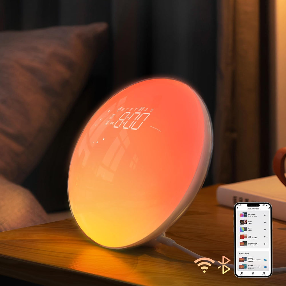 Sunrise alarm clock with wake up light displaying a warm glow on a bedside table with a smartphone nearby.