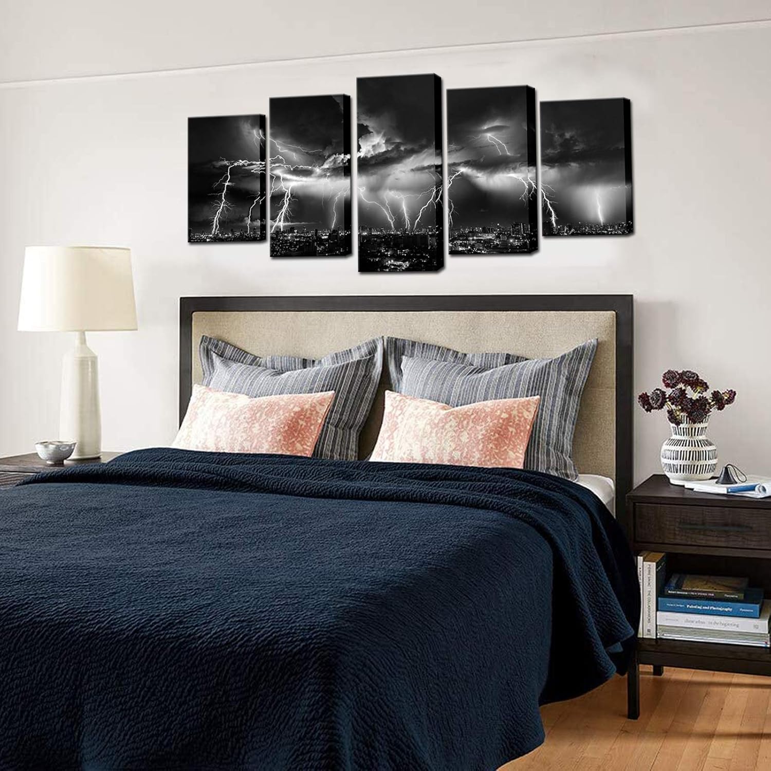 Black and white lightning wall art depicting a stormy city night view above a cozy bedroom with decorative pillows.