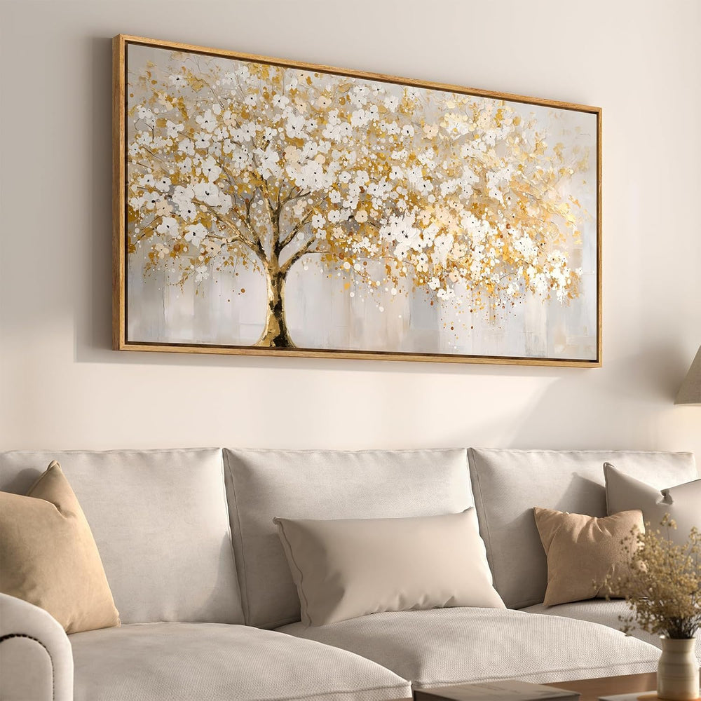 Large gold tree of life wall art 30x60 framed canvas print displayed above a beige sofa in a modern living room.