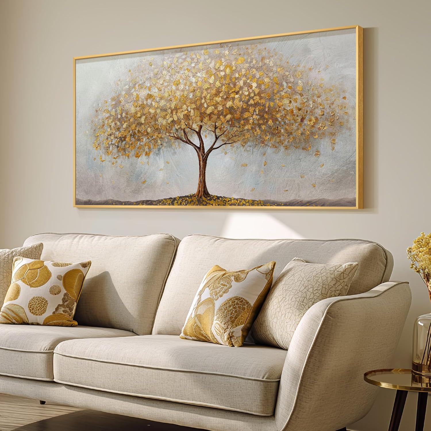 Large gold tree of life wall art displayed above a beige sofa with decorative pillows.